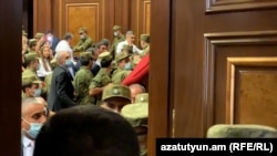 The prime minister's presentation was briefly interrupted by a scuffle in parliament.