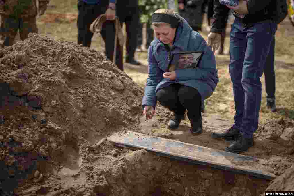 Iryna Tromsa throws soil into the grave of her son, Bohdan, 24, in Bucha on April 23. Bohdan was a Ukrainian paratrooper killed fighting Russian troops in the northeast of his country. 