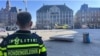 A Dutch police officer on March 27 looks on as a medical helicopter arrives in Amsterdam after stabbing attack that injured five.