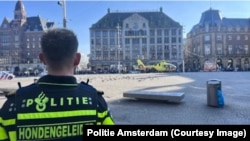 A Dutch police officer on March 27 looks on as a medical helicopter arrives in Amsterdam after stabbing attack that injured five.