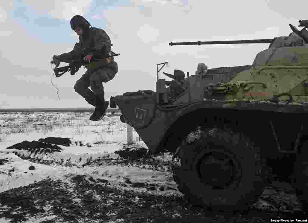 A Russian soldier leaps from an armored vehicle during drills at the Kuzminsky range, in Russia's southern Rostov region, on January 26. The military firing range is around 50 kilometers from the border with Ukraine. 