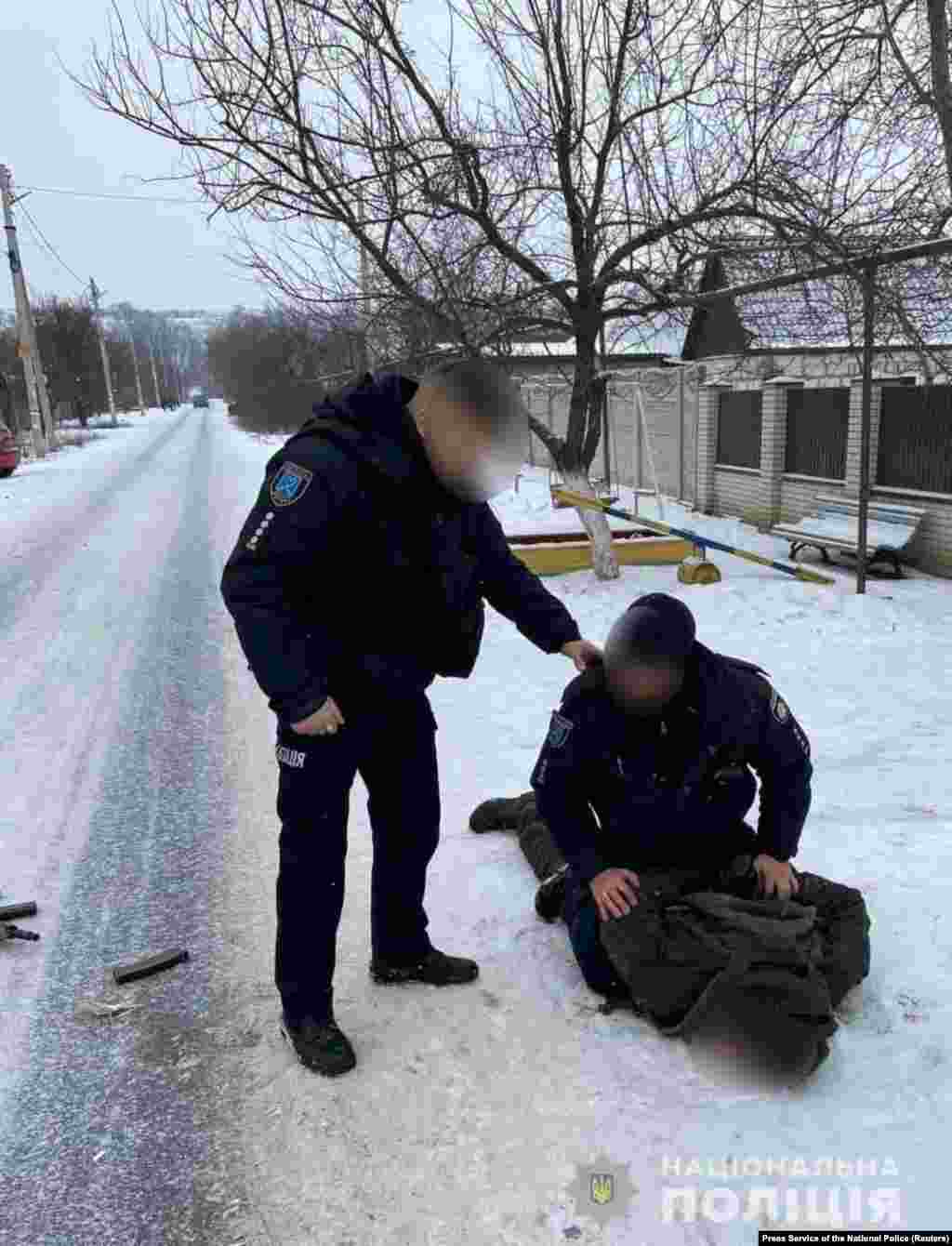 Ukrainian police detain a National Guard soldier after he allegedly gunned down five people at a military factory in the Dnipropetrovsk region on January 27. 