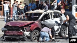 Ukrainian police and Security Service experts examine the charred car of journalist Pavel Sheremet, after he was killed by a car bomb in Kyiv on July 20, 2016.