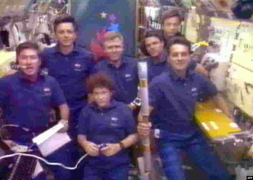 Space shuttle "Columbia" crew member Richard Linnehan (right) holds the Olympic torch in July 1996, the first relay tour into space.