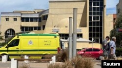 People walk next to an ambulance in front of the hospital in Egypt where the bodies of Russian tourists killed in the submarine incident are kept. 