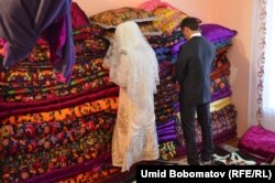 The couple face the wall while aunts and other female relatives make a bed out of ornate cushions.