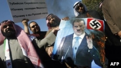 Newly elected Kuwaiti deputy Walid Tabtabai (left) holds a burning portrait of Russian President Dmitry Medvedev during a protest in front of the Russian Embassy in Kuwait City on February 6.
