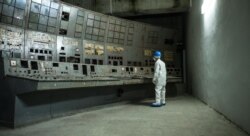 Adam Çernobyl AES-niň üsti örtülen reaktorynyň dolandyryş bölümine seredýär.