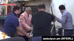 Armenia - A screenshot of "Zhoghovurd" newspaper video of Vagharsh Abrahamian (second from left), the owner of a jewelry market in Yerevan, removing stalls used traders participating in anti-government demonstrations, 25Sep2014.