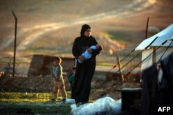 An IS bride carries her child at the refugee camp in the Syrian village of Ain Issa. (file photo)