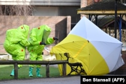 Members of the U.K. emergency services put a tent over the bench where a man and a woman were found in critical condition in Salisbury in March 2018.