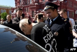 Roman Roslovtsev, wearing his trademark Putin mask, is detained by police during a "performance" in Red Square on May 14.