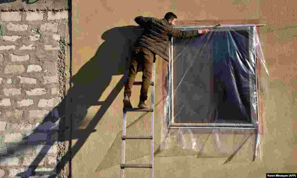 A resident repairs the shattered window of his apartment on November 24. 
