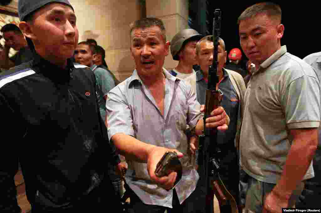 Supporters of Atambaev brandish an assault rifle and a clip of ammunition. 