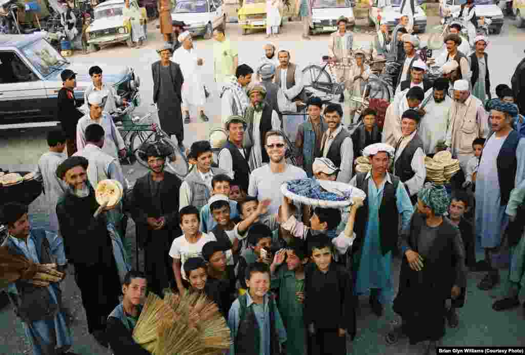 Me (in sunglasses) amid a smiling crowd of Afghans. I always received a warm welcome while traveling in northern Afghanistan and was regularly invited into people's humble homes as an honored guest where my hosts would offer me lamb or goat, often after slaughtering their only source of meat for the occasion.