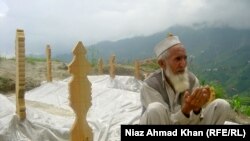 Eighty-year-old Gul Shirin prays next to the fresh graves of 13 family members who died in flooding in Swat Valley in August.