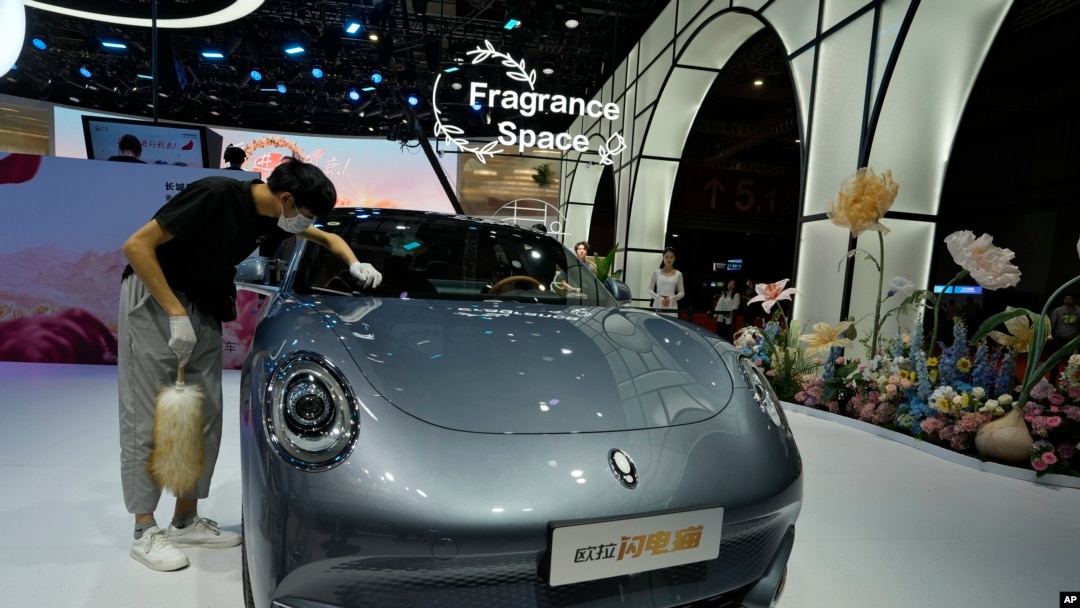 Radnik pored automobila brenda Ora, kineske proizvodnje, tokom sajma u Šangaju 2023. 