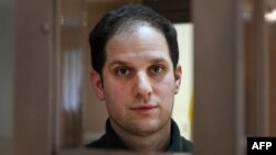U.S. journalist Evan Gershkovich, arrested on espionage charges, looks out from a defendants' cage before a hearing to consider an appeal at the Moscow City Court in Moscow on February 20.