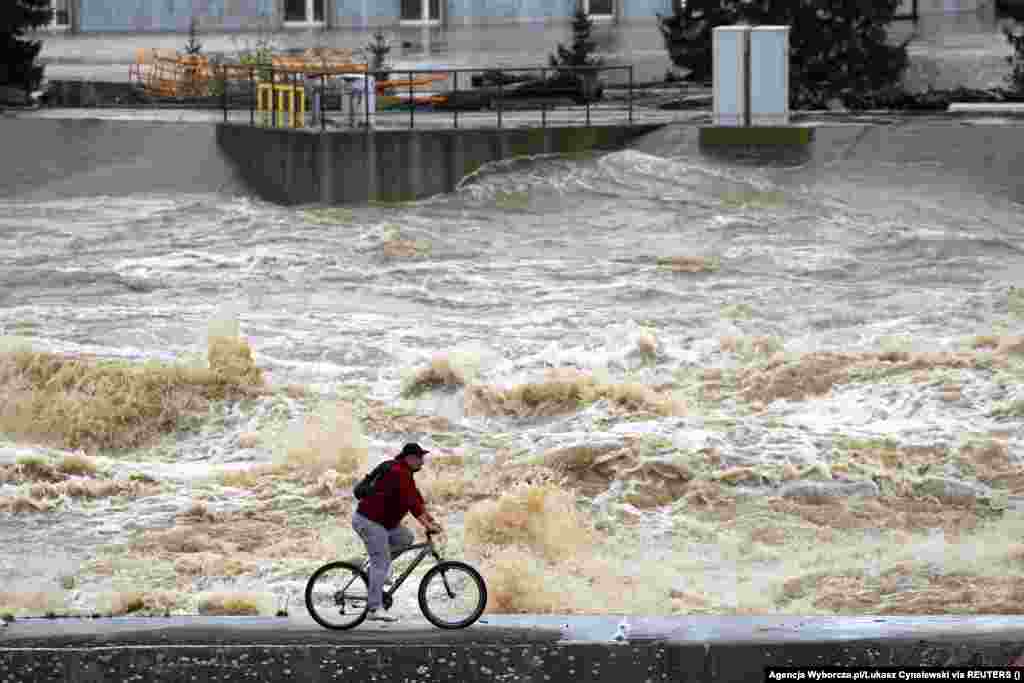 A man rides his bicycle past elevated water levels at the Glebinow hydroelectric power plant in Nysa, Poland. Two dams reportedly failed amid what local authorities said was a "critical" situation.