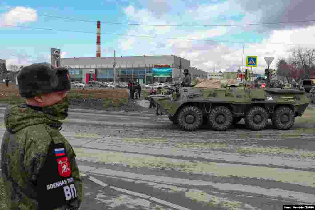 A masked soldier watches a BMP-3 infantry fighting vehicle passing by. 