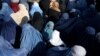 A girl waits among a crowd of Afghan women waiting to receive bread from a Kabul bakery.