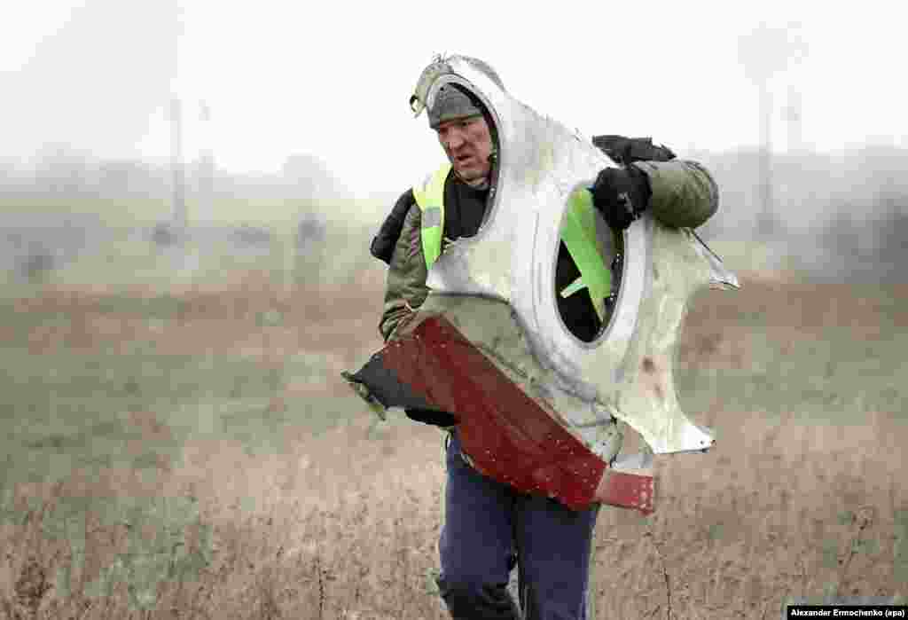 A November 2014 photo of a man carrying a piece of the aircraft from the crash site inside Ukrainian territory held by Russia-backed separatists. Dutch inspectors commissioned the emergency services of the separatist group that calls itself the Donetsk People's Republic to collect the wreckage after saying the area was too dangerous for their staff. 