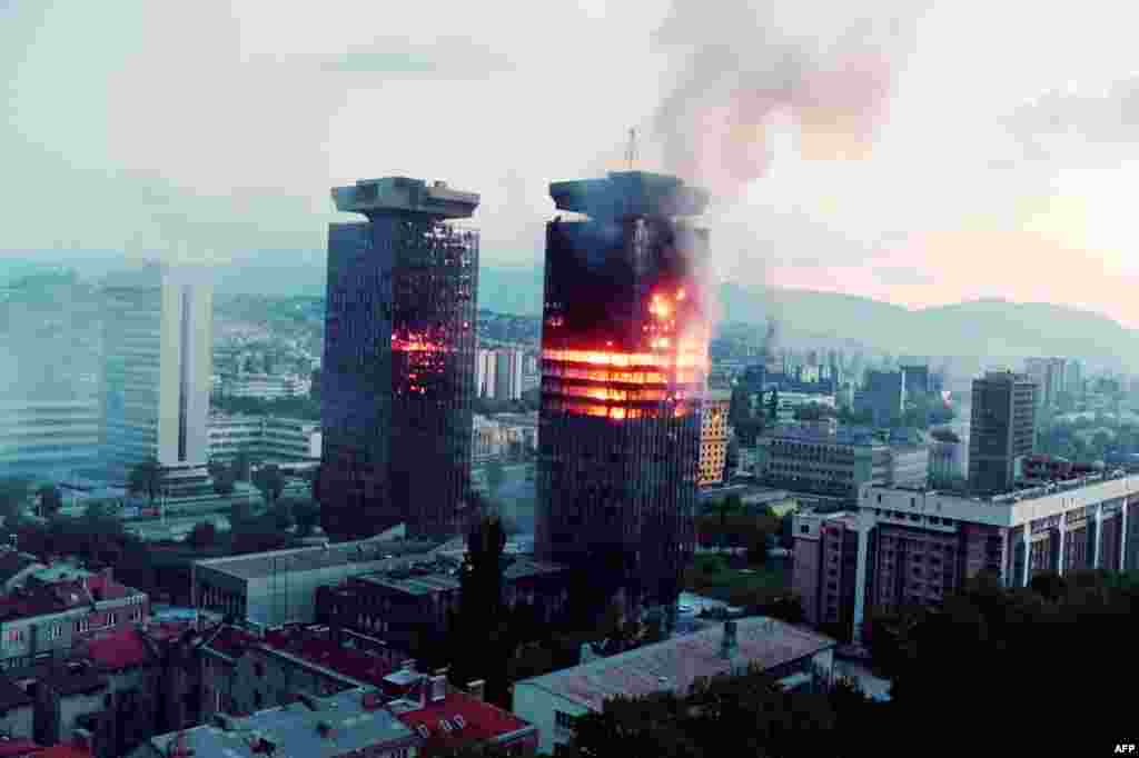 The UNIS twin towers burn along 'Sniper Alley' in downtown Sarajevo as heavy shelling and fighting raged in the Bosnian capital on June 08, 1992. Nicknamed 'Momo' and 'Uzeir' after a popular ethnic Bosniak and Serb comedy duo, the structures were heavily damaged during the siege of Sarajevo but remained standing to became a symbol of the city's resilience.