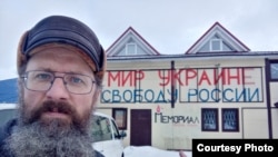Dmitry Skurikhin stands in front of his store, which calls for peace in Ukraine and freedom in Russia.