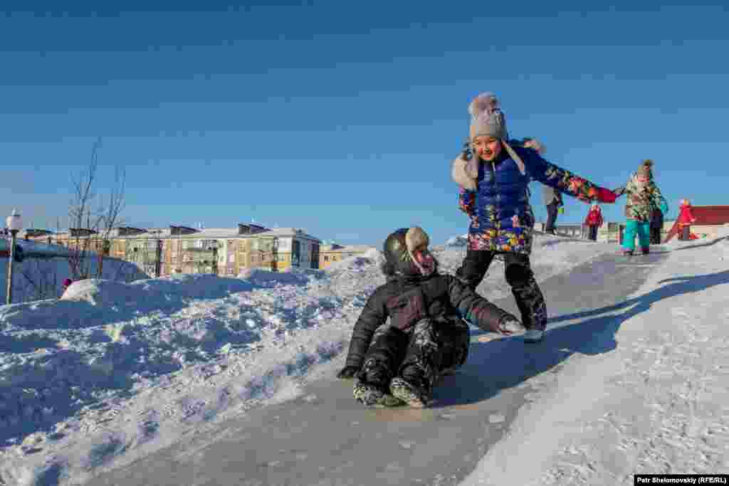 Local children slide down a snowhill in a central square in Vorkuta. 