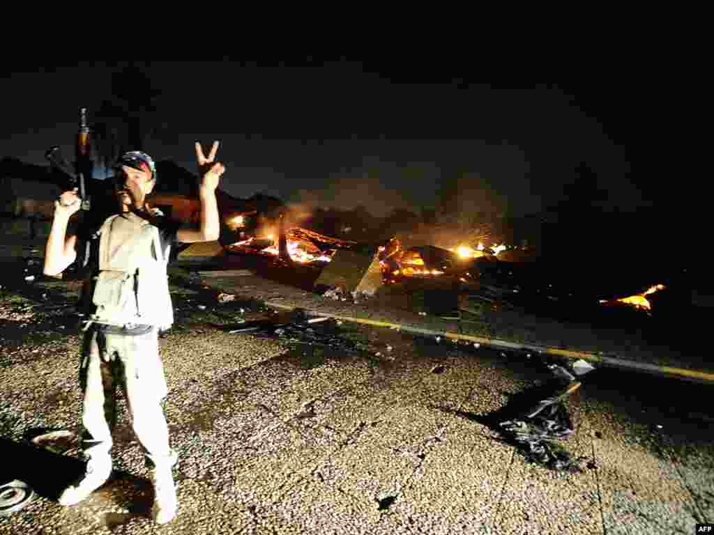 A Libyan rebel flashes the victory sign after overrunning Muammar Qaddafi's fortified Bab al-Aziziya headquarters.