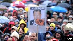 Employees of Hungarian radio station Klubradio and their supporters hold umbrellas and a poster with a photo of Hungarian Prime Minister Viktor Orban reading, "Don't you see that you bit off more than you can chew?" at a demonstration for the freedom of speech in Budapest on February 24, 2013