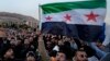 Syrian citizens wave the revolutionary flag and shout slogans as they celebrate in Damascus on December 9.