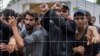 Migrants stand behind a fence inside a newly built refugee camp south of Vilnius in August 2021.