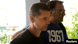 Aleksandr Vinnik is escorted by plainclothes police officers to a court in Thessaloniki in July.