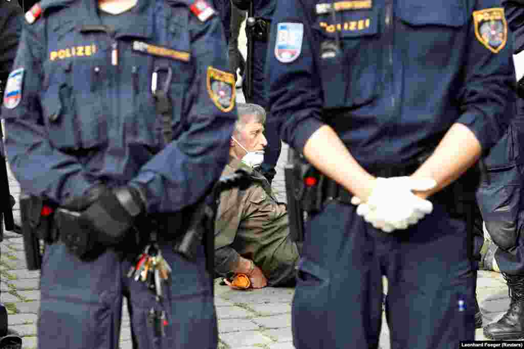 Беткапчан кишини кармап жаткан полиция кызматкерлери. 24-апрелде Вена шаарынын 200гө жакын тургуну бийликтин коронавирусту токтотуу үчүн көрүлүп жаткан чараларына нааразылыгын билдирип митингге чыгышкан. 