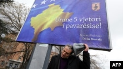 Un etnic albanez în faţa unui billboard cu inscripţia "La Mulţi Ani Kosovo, cu ocazia celei de a cincea aniversări a independenţei", la Pristina, 13 februarie 2013