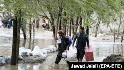 Afghan men carry their belongings as they evacuate from their residential area after flash flooding in the west of Kabul on April 16. 