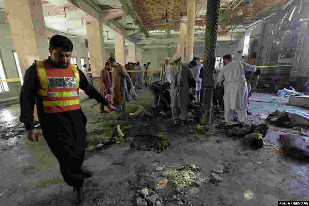 Oficialii poliției și membrii echipelor de salvare colectează probe materiale și resturile umane de la locul exploziei unei bombe artizanale, într-o școală islamică din Peshwar, 27 octombrie 2020