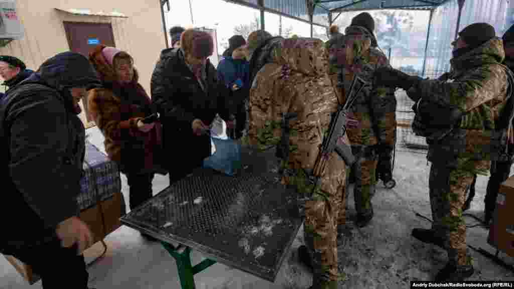 Ukrainian soldiers search belongings before people can begin the long march to separatist-held territory.