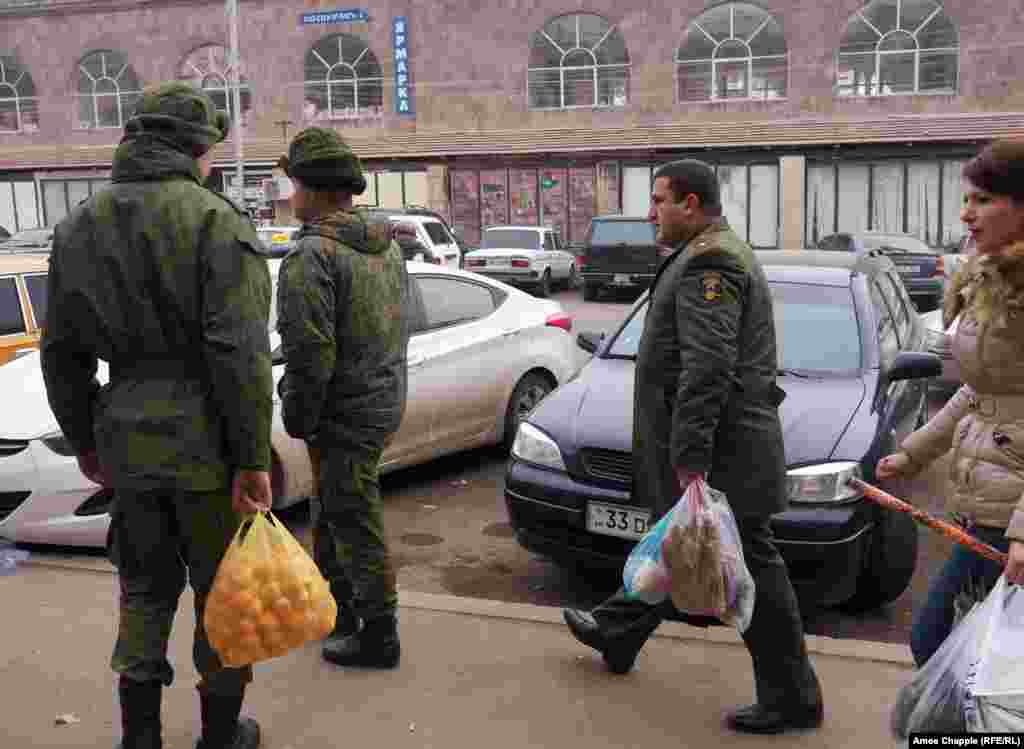 An Armenian Army officer (right) walks past Russian soldiers in Gyumri's center. The officer made eye contact with the soldiers, but no greetings were exchanged.