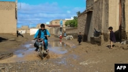 An Afghan motorcyclist drives through a sodden street following heavy rains and flash flooding in the Guzara district of Herat Province earlier this week.