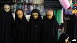 Mannequins dressed in chadors are displayed in a shop in front of a shrine at the city of Qom.