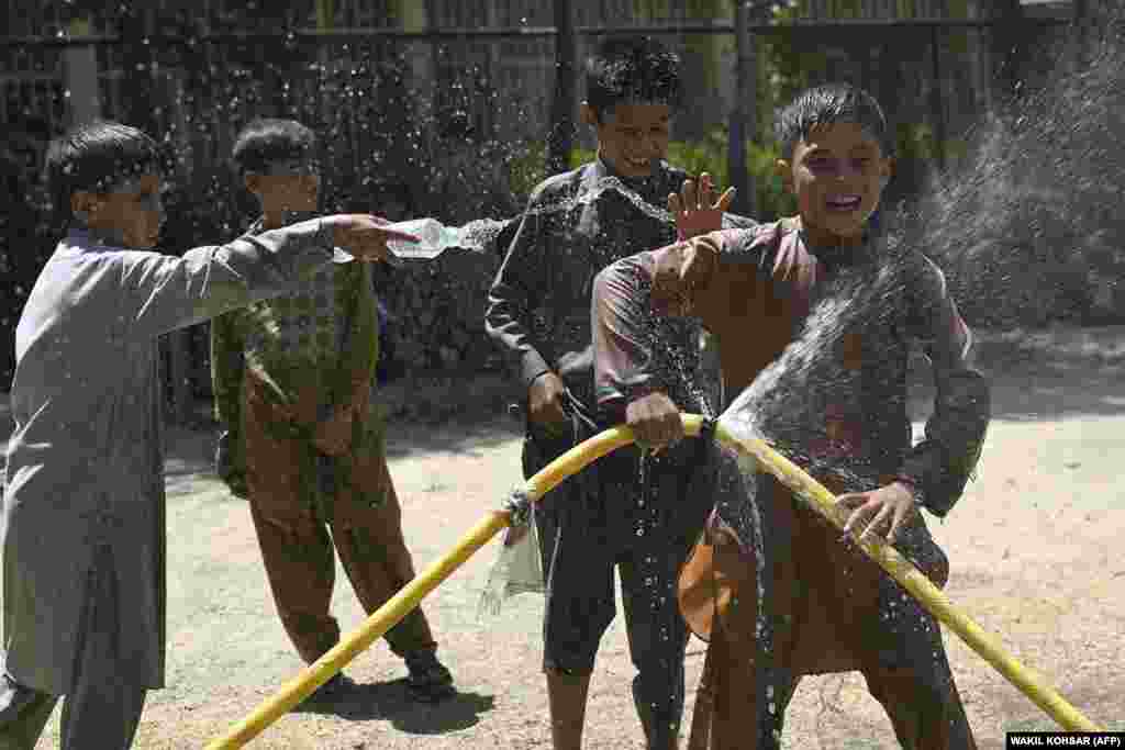 Afghan children cool off while playing with a hose at the Shahr-e Naw park in Kabul.