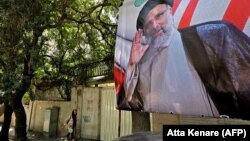 A pedestrian walks by a poster of judiciary chief and presidential candidate Ebrahim Raisi in Tehran on June 1.
