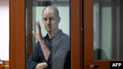 U.S. journalist Evan Gershkovich, accused of espionage, gestures from inside a glass defendants' cage prior to a hearing in Yekaterinburg's Sverdlovsk Regional Court on June 26.