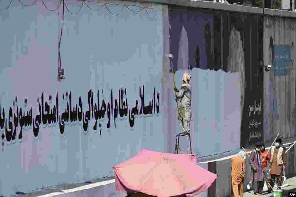 A wall is painted white with a message declaring: “For an Islamic system and independence, you must endure tests and stay patient.”